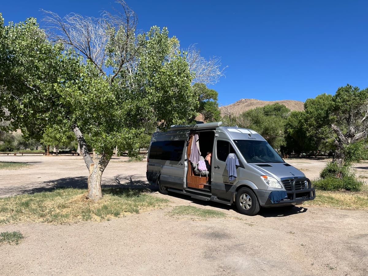 Silver camper van parked under shade tree at Diaz Lake Campground near Lone Pine CA